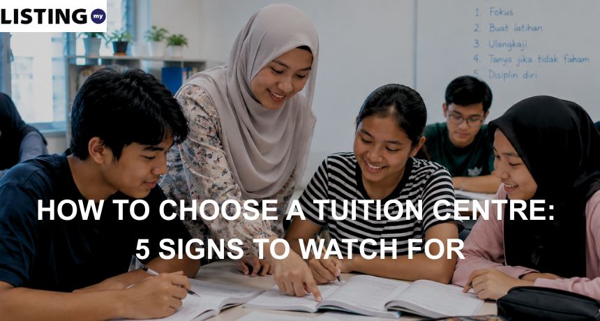 A smiling female Malay tutor helps a small group of Malaysian students study in a tuition classroom.