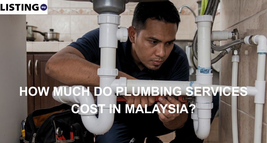 A professional plumber using a pipe wrench to repair white PVC drainage pipes under a kitchen sink.